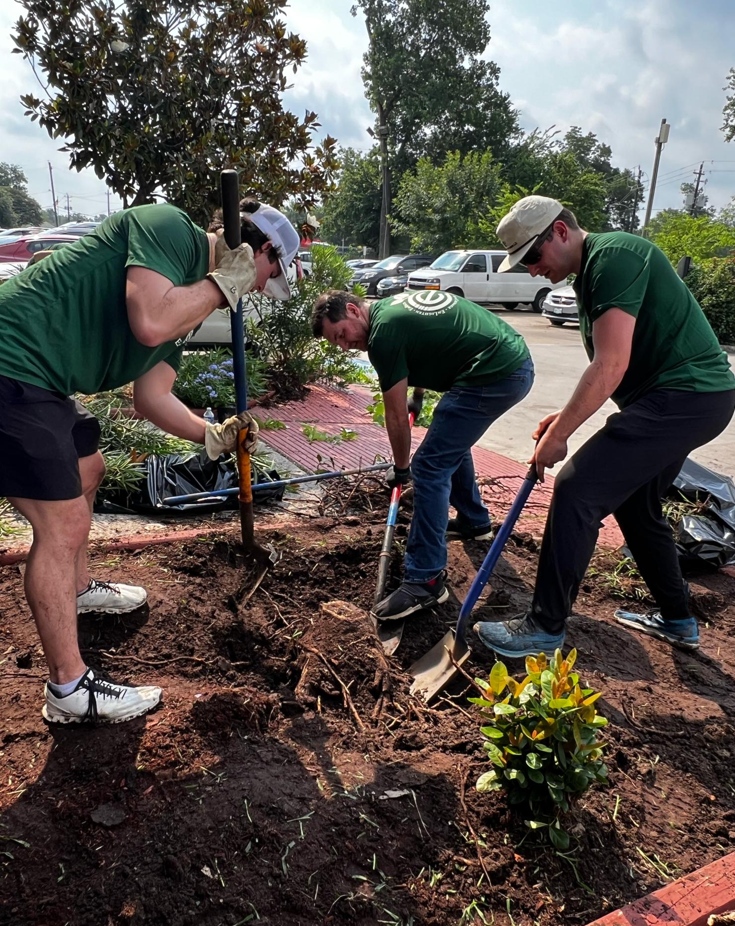 Austin Ritchie (L), Ben Bryson (M) and Nathanael Robinson (R) work together to remove a large tree stump at the entrance of the Bonita House campus.