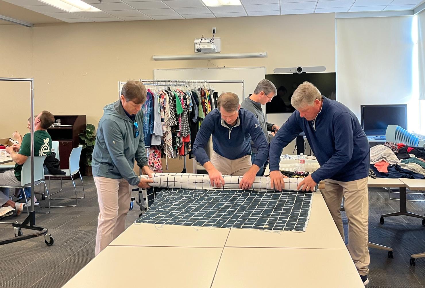 Brad Thielemann (L), George Purgason (M) and Doug Swanson (R) work on measuring and cutting donated fabric that MAM will sell in their resale shop.