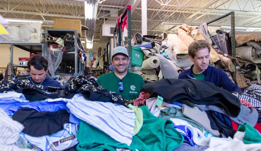 Austin Ritchie (L), Craig Friou (M) and Andrew Perry (R) sort through clothing donations in MAM’s warehouse.