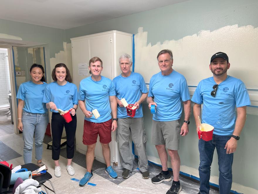 Employees pose for a picture as they make progress painting a small group activity room.